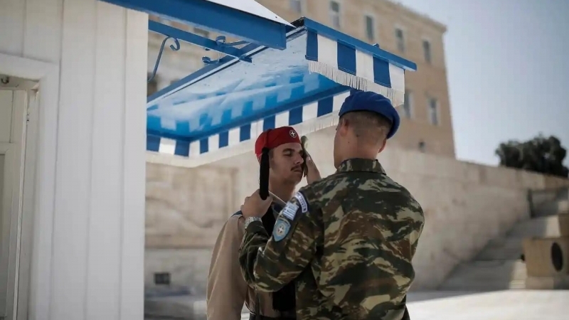 Fotografia dimineții - Un ofițer îi șterge fața transpirată unui soldat aflat în gardă, în fața clădirii parlamentului din Atena, Grecia