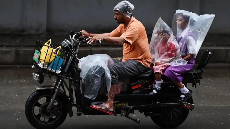 Fotografia dimineții - Un bărbat din India își transportă copiii pe motocicletă în timpul unei ploi musonice